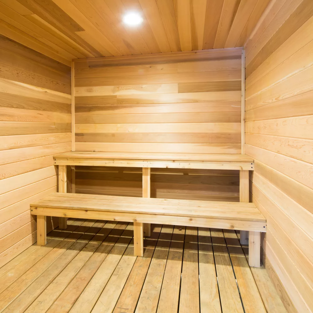 Empty sauna room with light wood walls, floor, and tiered benches.