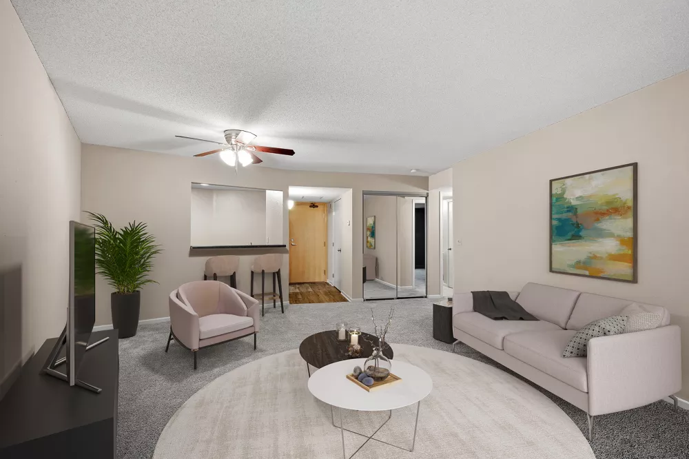 Modern living room with a pink sofa, armchair, two coffee tables on a round rug, and a bar area.