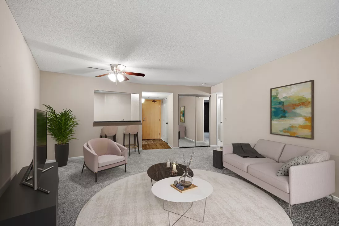 Modern living room with a pink sofa, armchair, two coffee tables on a round rug, and a bar area.